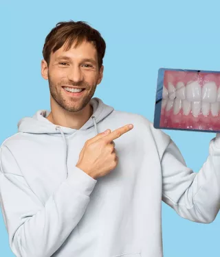 Man holding a tablet with an image of straight teeth.