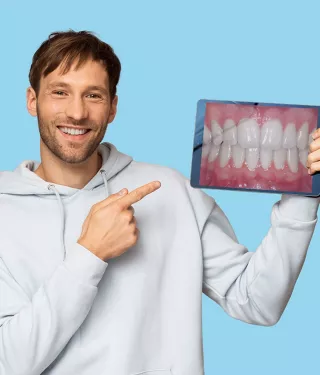 Man holding a tablet with an image of straight teeth.