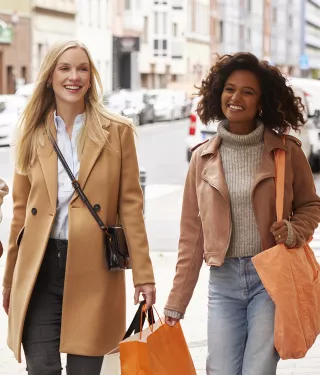 Smiling women walking together holding shopping bags