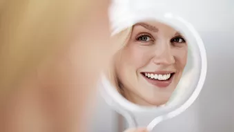 Woman admiring her whitened teeth in a mirror
