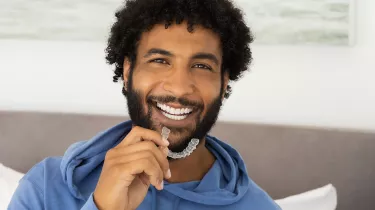 Man in bedroom holding Clear Aligners