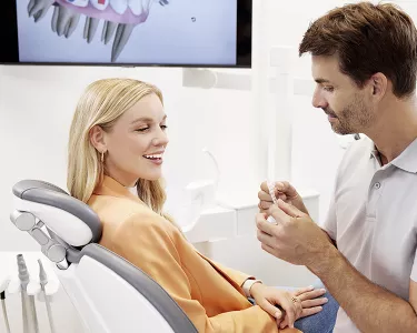 Orthodontist showing a Spark clear retainer to his female patient